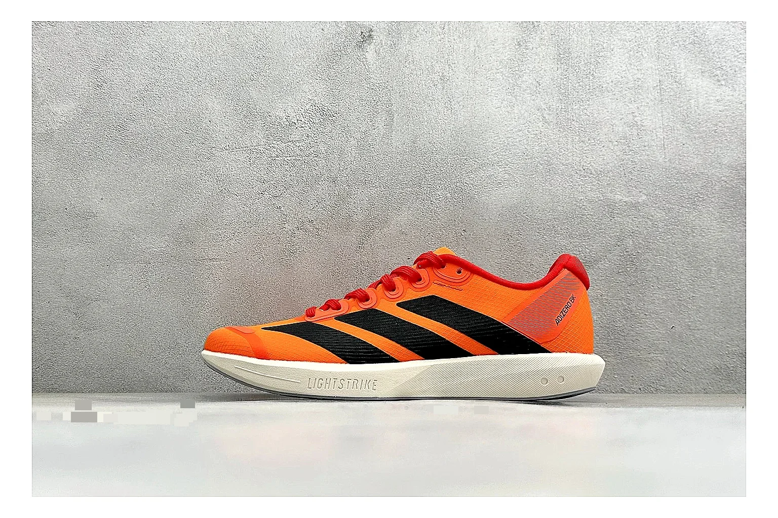 Adidas Adizero Orange Black comparison photo showing orange runner upper, black three-stripe contrast, lightweight racing shape, and thin performance sole