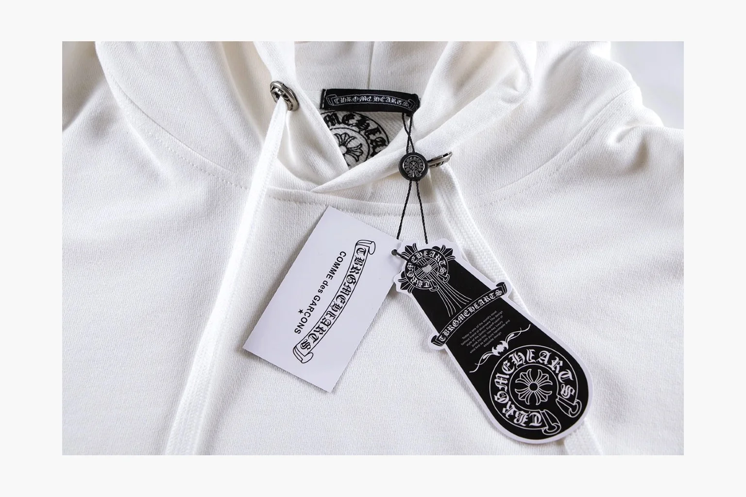 Chrome Hearts White Cross Zip Hoodie comparison photo showing white cotton fleece zip hoodie, cross back artwork, drawcord hood, sleeve print, front zipper, and ribbed trim