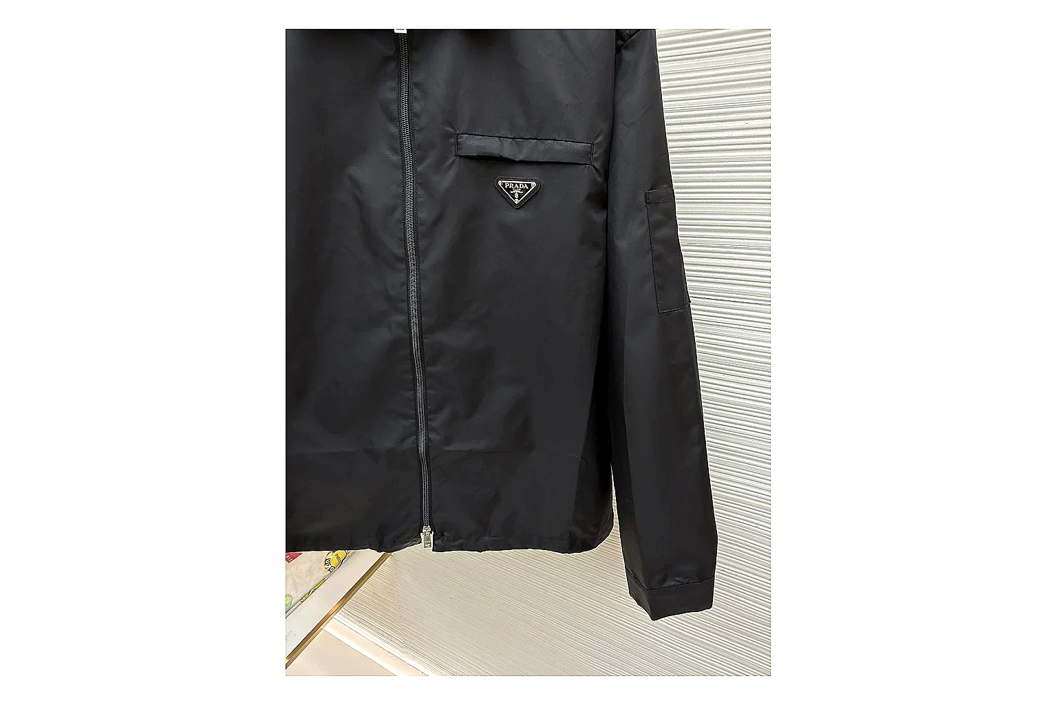 Prada Re-Nylon Hooded Jacket Black Jacket comparison signal photo with black Re-Nylon hooded jacket with recycled-nylon texture, hood structure, zipper line, sleeve cuffs, and light shell shape